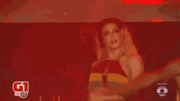 a woman in a bikini is dancing in front of a red background with a g1 logo on it