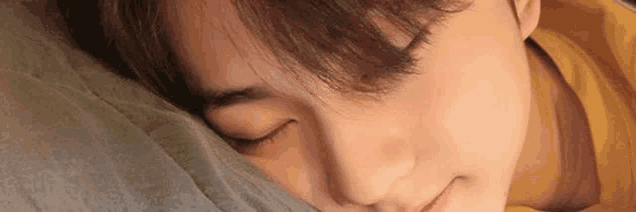 a close up of a young man sleeping on a pillow with his eyes closed .