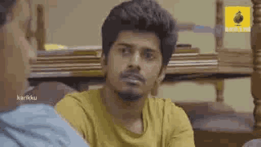 a man is sitting at a table talking to another man .