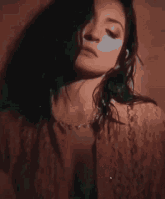 a close up of a woman 's face with her eyes closed wearing a lace top