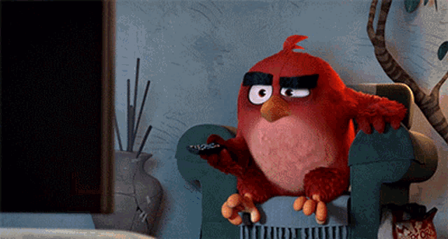 an angry bird sits in a chair holding a remote control