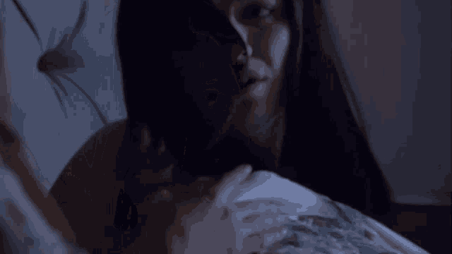 a woman with long dark hair is laying in bed