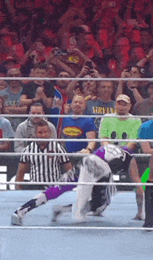 a man in a nirvana shirt watches a wrestler fall