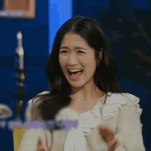 a woman is making a funny face with her mouth open and her hands in the air .
