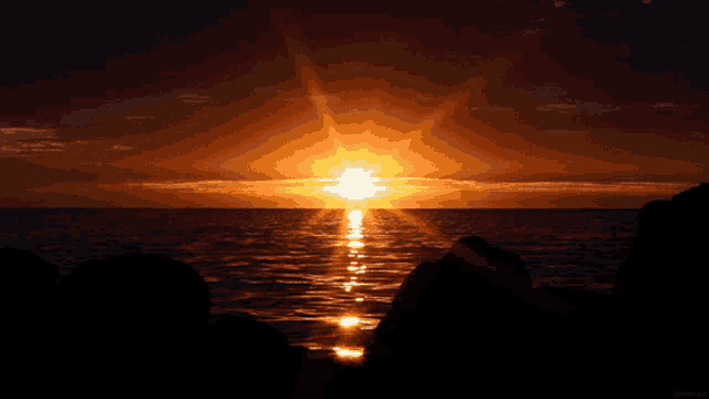 a sunset over a body of water with the sun shining brightly through the clouds