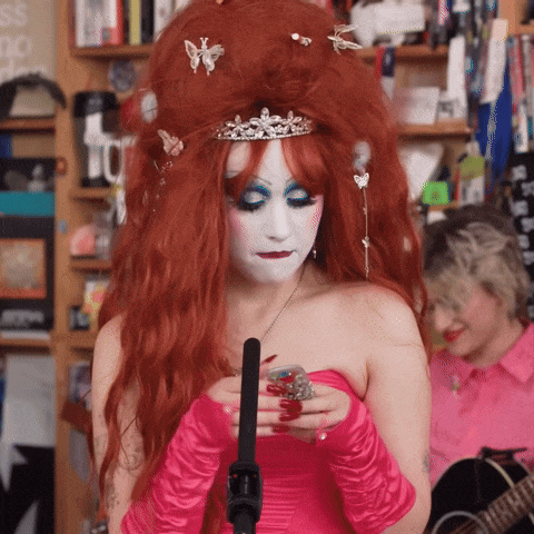 a woman with red hair wearing a pink dress and gloves