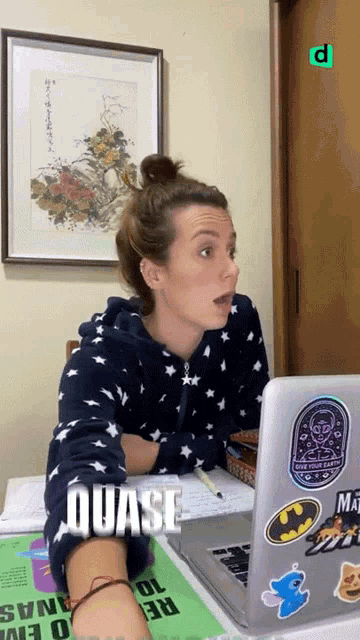 a woman sitting in front of a laptop with the word quase written on the screen