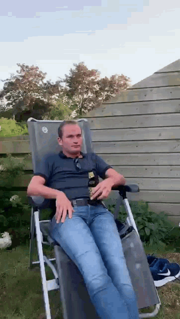 a man is sitting in a chair with a bottle of beer in his hand