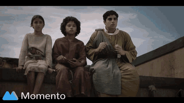 a group of people sitting on a wall with the word momento in the upper right corner