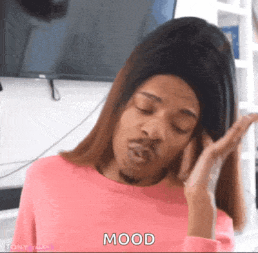 a woman in a pink sweater is making a funny face and the word mood is on the screen