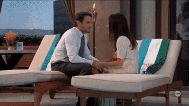 a man and a woman are sitting on lawn chairs holding hands