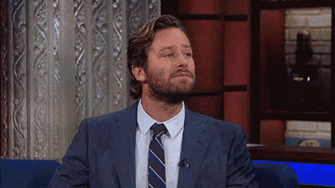 a man with a beard wearing a suit and tie is sitting in a chair .