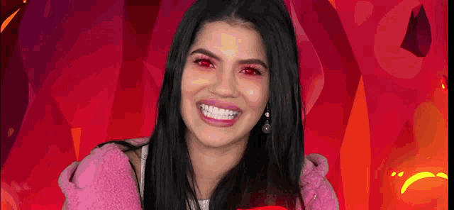 a woman with red eyes is smiling and wearing a pink jacket .