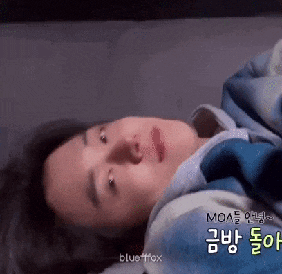 a close up of a person laying on a bed with a blue blanket on their head .