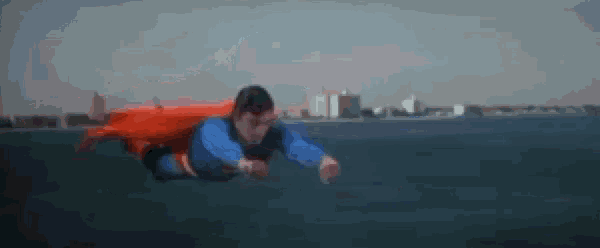 superman is flying through the air over the ocean .