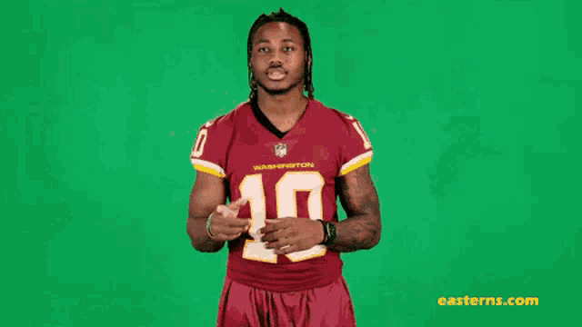 a man in a washington redskins jersey is standing in front of a green background