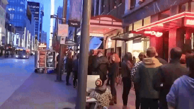 a crowd of people are walking down a street in front of a building that has a sign that says club on it .