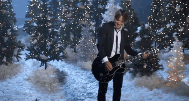 a man in a suit and tie playing a guitar in the snow