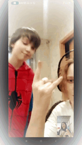 a phone screen shows a boy in a spiderman costume giving a peace sign