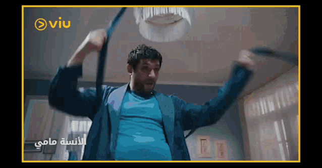 a man in a blue shirt is dancing in a room with a viu logo on the bottom right