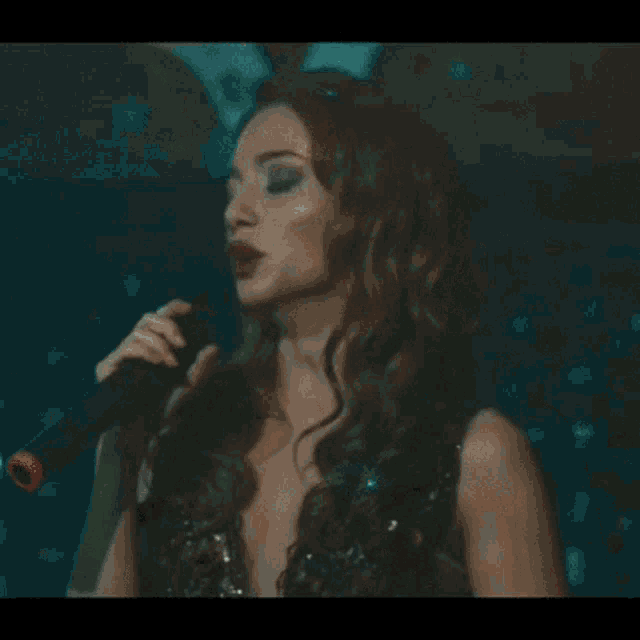 a woman in a long dress is dancing on a stage in a dark room