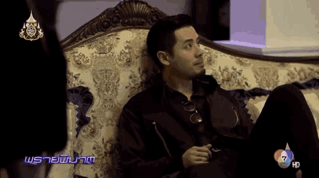 a man sits on a couch in front of a screen that says 7 hd