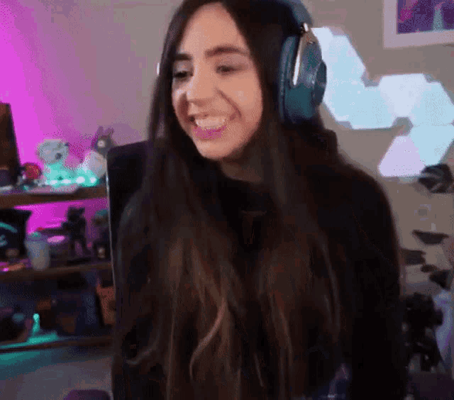 a woman wearing headphones is smiling and looking at the camera in a room .