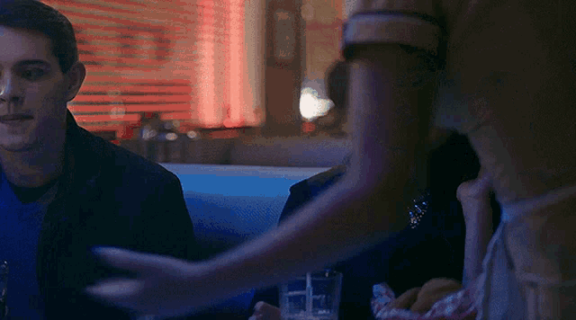 a man and a woman are sitting at a table in a diner at night