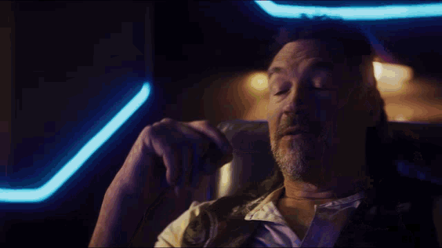 a man with a beard is drinking from a bottle in a dark room