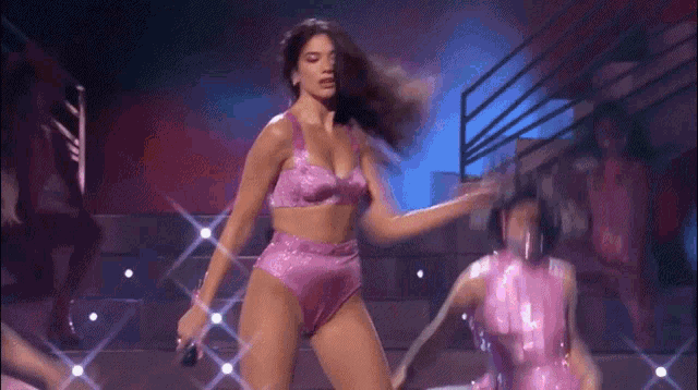a woman in a pink bikini is dancing on a stage .