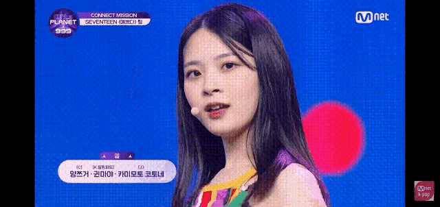 a girl with long hair is standing in front of a microphone on a blue background .