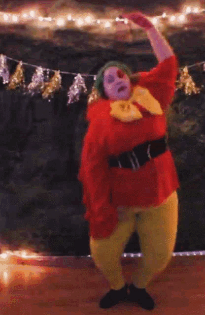 a woman in a clown costume is dancing in front of christmas lights