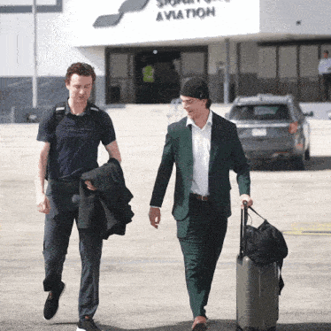 two men walking in front of a building which says aviation