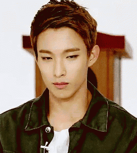 a young man wearing a green jacket and a white t-shirt