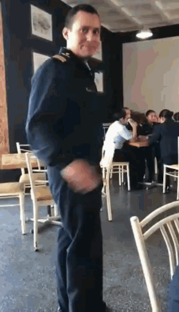 a man in a military uniform stands in a restaurant with people sitting at tables