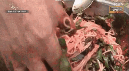a close up of a person holding a spoon over a pile of noodles .