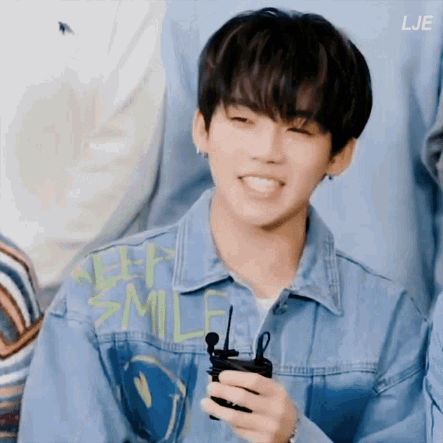 a young man wearing a denim jacket that says keep smile is smiling