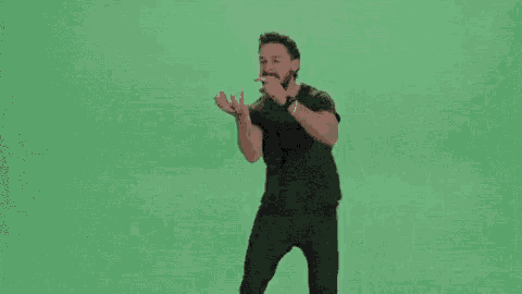 a man with a beard is standing in front of a green screen and saying solo hazlo .