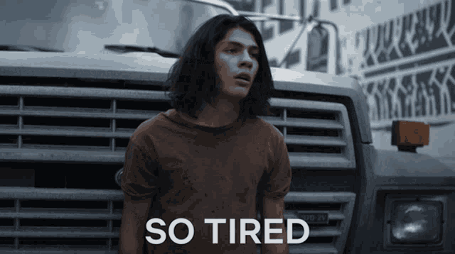 a man is standing in front of a truck with the words so tired written on it