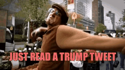 a man is standing in front of a crowd with a sign that says just read a trump tweet .