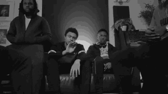 a black and white photo of a group of young men sitting on a couch with one wearing a puma shirt