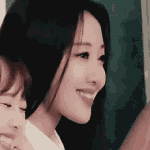 a close up of a woman 's face with her eyes closed and a smile on her face .
