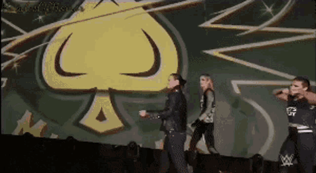 a group of people are standing on a stage in front of a large ace of spades .