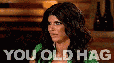 a woman in a green dress is sitting in front of a bar and says `` you old hag '' .