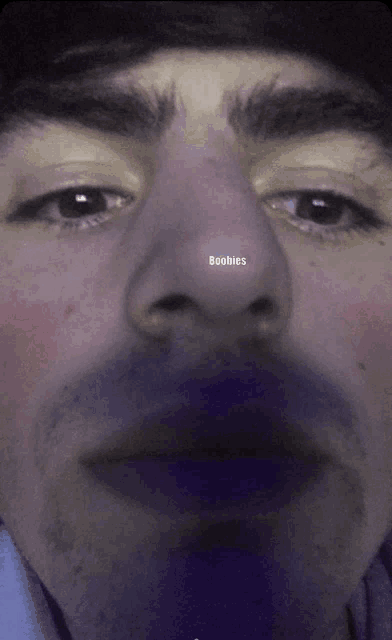 a close up of a man 's face with the word boobies written on it