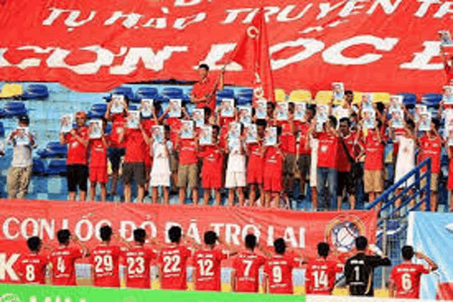 a group of soccer players are standing in front of a large red banner that says con loc do da tro lai .