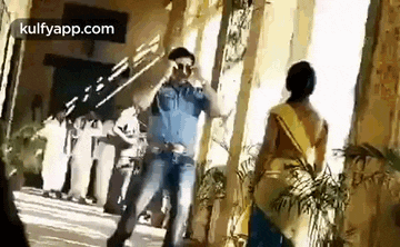 a man in a police uniform is dancing in front of a woman in a sari .