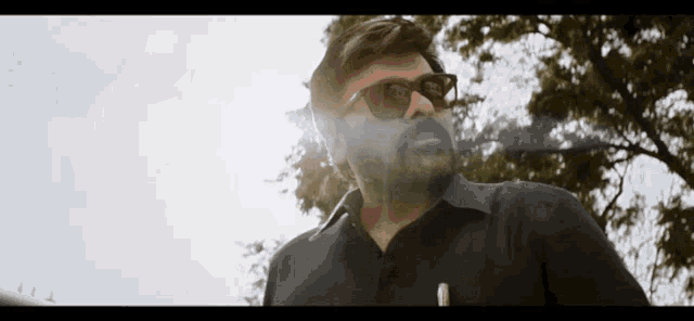 a man wearing sunglasses is smoking a cigarette