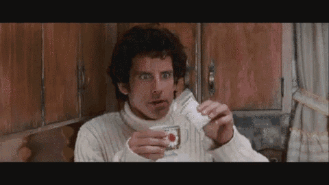 a man in a sweater is holding a cup of coffee in his hand .
