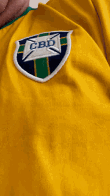 a man wearing a yellow shirt with cbd embroidered on it